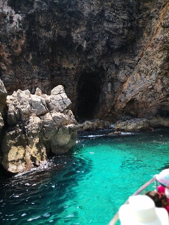 Barca all'ingresso di una grotta marina dalle acque turchesi