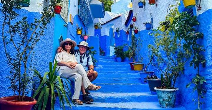 Coppia seduta sulle scalinate blu della medina di Chefchaouen