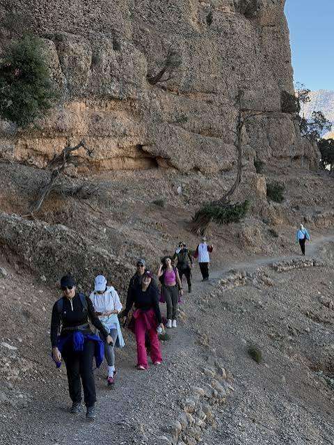 Gruppo in cammino lungo il sentiero sotto la parete rocciosa