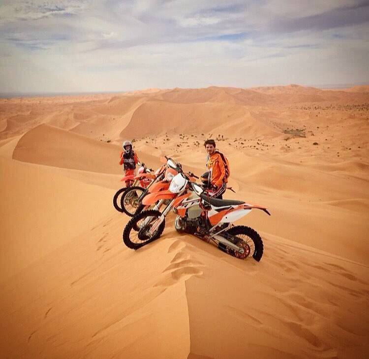 Moto da enduro in cima a una duna nel deserto
