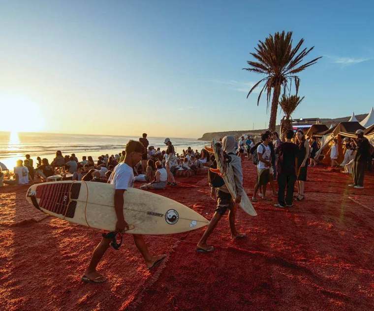 Surfisti al tramonto sulla sabbia rossa di Taghazout