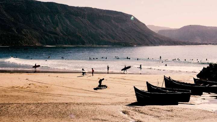 Surfisti e barche di pescatori sulla spiaggia di Taghazout