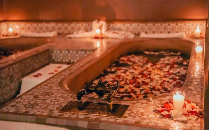 Vasca di un hammam illuminata da candele e petali